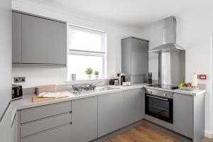 a kitchen with white cabinets and a sink and a window at Stunning Apartment In Peaceful Central Neighbourhood, Free Private Parking in Cardiff