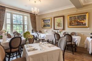 a restaurant with white tables and chairs and windows at Kells Bay House and Gardens in Kells