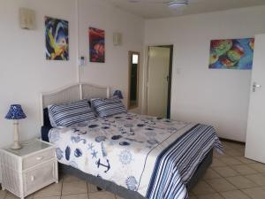 a bedroom with a bed with a blue and white comforter at 197 Stella Maris in Amanzimtoti
