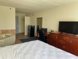 a hotel room with a bed and a desk with a television at Miami Gardens Inn & Suites in Miami