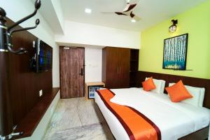 a bedroom with a large bed with orange pillows at Grand Padappai Residency in Chennai