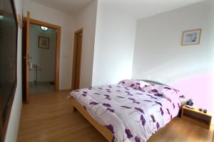 ein Schlafzimmer mit einem Bett mit einer lila Bettdecke in der Unterkunft Guest House Ivac Inn Zagreb Airport in Velika Gorica