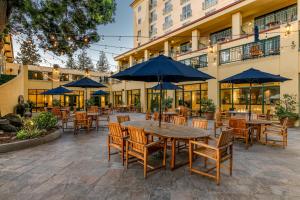 an outdoor patio with tables and chairs with blue umbrellas at Crowne Plaza Cabana Hotel by IHG in Palo Alto