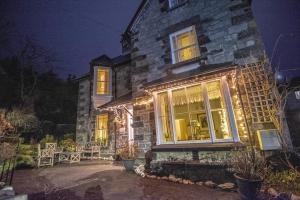 Una casa de piedra con luces de Navidad. en Garth Dderwen, en Betws-y-coed