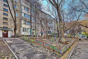 an empty park in front of a building with a tree at Апартаменты на улице Клочкова, 128 in Almaty