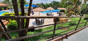 een balkon met uitzicht op een zwembad met tafels en parasols bij Apartamentos Ecologic PARK - Caldas Novas in Caldas Novas