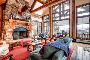 a living room with a large stone fireplace at Bachelor Gulch Collection by East West Hospitality in Avon