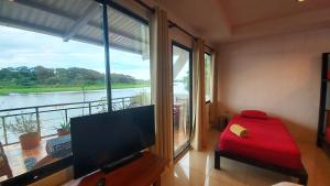 a living room with a tv and a large window at Tortuguero Adventures GuestHouse in Tortuguero