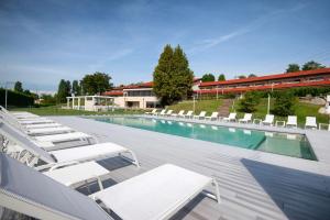 basen z białymi leżakami obok budynku w obiekcie Hotel Horizon Wellness & Spa Resort - Best Western Signature Collection w mieście Varese