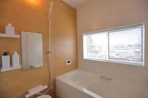 a bathroom with a tub and a toilet and a window at Villas Asama no Iori in Fujiyoshida