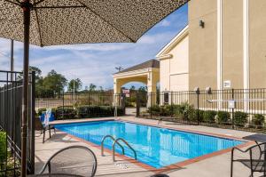 einen Pool mit Stühlen und einem Sonnenschirm in der Unterkunft Quality Inn & Suites Slidell in Slidell