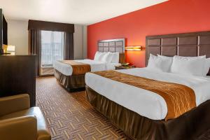 2 camas en una habitación de hotel con paredes rojas en Sonesta Essential Minot, en Minot