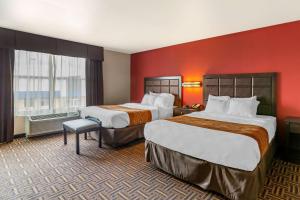 duas camas num quarto de hotel com paredes vermelhas em Sonesta Essential Minot em Minot