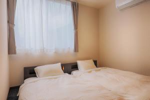 two beds in a room with a window at Villas Asama no Iori in Fujiyoshida