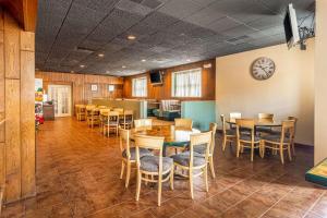 Quality Inn & Suites في Virginia: غرفة طعام مع طاولات وكراسي وساعة