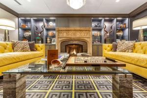 a living room with yellow couches and a fireplace at Cambria Hotel Houston Downtown Convention Center in Houston