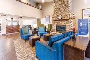 a lobby with a blue couch and chairs and a fireplace at Comfort Inn in Waukesha