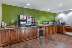a kitchen with wooden cabinets and a green wall at Quality Inn & Suites Longview I-20 in Longview