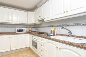 a kitchen with white cabinets and a sink and a microwave at Poolbeach V in Moraira