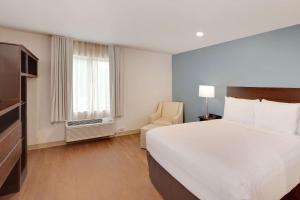 een hotelkamer met een bed en een stoel bij WoodSpring Suites Las Colinas - Northwest Dallas in Irving