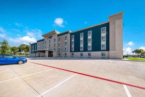 a building with a car parked in a parking lot at WoodSpring Suites Dallas Plano Central Legacy Drive in Plano