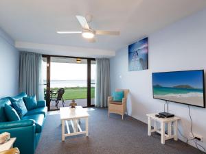 a living room with a blue couch and a tv at Harbourside 4 ground floor on the waterfront in Soldiers Point