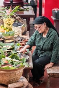 
a woman sitting at a table with a bunch of vegetables at Hotel Tugu Blitar in Blitar

