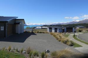 a road leading to a building with mountains in the background at Starview 88 Apartment in Lake Tekapo