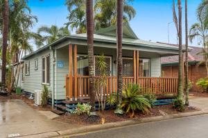 a green house with a porch with palm trees at Discovery Parks - Rockhampton in Rockhampton