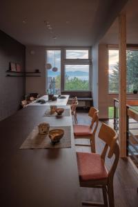 una cocina con una mesa larga con sillas y ventanas en MOKUREN en Furano