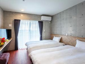 ein Hotelzimmer mit 2 Betten und einem Fenster in der Unterkunft Little Island Okinawa Nago in Nago