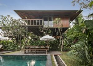 a house with a swimming pool and a bench and a house at Grün Canggu Garden in Canggu