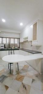 a white kitchen with a white table and a counter at Cozy Corner House #4 Bedroom #3 Bathroom in Ipoh