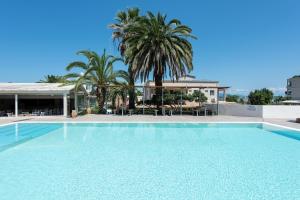 a large swimming pool with palm trees and a building at Anita in Perama