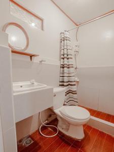 ein Badezimmer mit einem WC, einem Waschbecken und einem Spiegel in der Unterkunft Telesfora Beach Cottage in El Nido