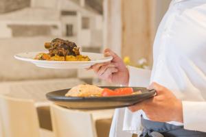 a chef is holding a plate of food at Hotel Jeni & Restaurant in Es Mercadal