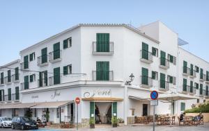 een groot wit gebouw met groene luiken bij Hotel Jeni & Restaurant in Es Mercadal