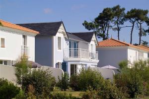 une rangée de maisons blanches avec des arbres et des buissons dans l'établissement Madame Vacances Les Maisons de Fontenelles, à LʼAiguillon-sur-Vie