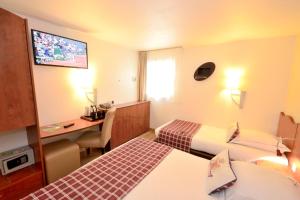 a hotel room with two beds and a desk at Greenhotels Roissy Parc des Expositions in Tremblay-En-France