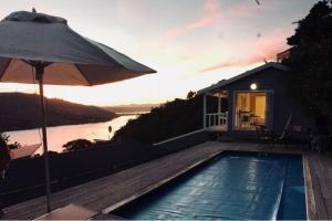 a house with a swimming pool and an umbrella at Knysna Heads Private Suite in Knysna