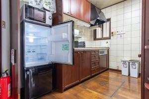 La cuisine est équipée d'un grand réfrigérateur et de placards en bois. dans l'établissement Guest house Fujinoyado Akebono - Vacation STAY 92428, à Fujiyoshida