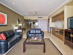 a living room with a black leather couch and a table at 2 BDR/Apt/Foxtel/WiFi/Pool/parking/Spa/Hervey Bay in Urangan
