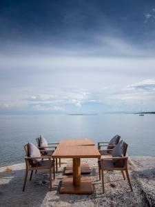 a wooden table and chairs with a view of the water at Rocky's Boutique Resort - Veranda Collection Samui in Lamai