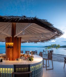 a restaurant with an umbrella on the beach at Rocky's Boutique Resort - Veranda Collection Samui in Lamai