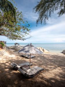 an umbrella and lounge chairs on a beach at Rocky's Boutique Resort - Veranda Collection Samui - SHA Extra Plus in Lamai