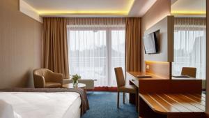 ヤスタルニャにあるHotel Dom Zdrojowy Resort & SPAのベッドとデスクが備わるホテルルームです。