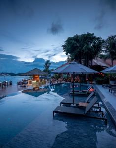 a swimming pool with chairs and umbrellas at night at Rocky's Boutique Resort - Veranda Collection Samui in Lamai