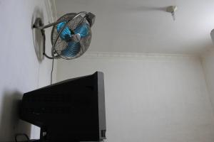 uma ventoinha pendurada numa parede ao lado de uma televisão em Penginapan Transit Tomato em Tanjungmorawa