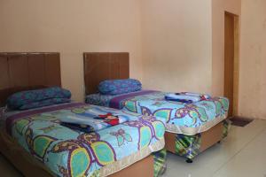 duas camas sentadas uma ao lado da outra num quarto em Penginapan Transit Tomato em Tanjungmorawa