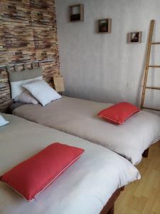 two beds in a room with red pillows on them at maison aux volets bleus in Quévert